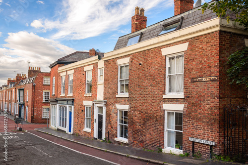 Row of old British brick terraced houses along a street at sunset