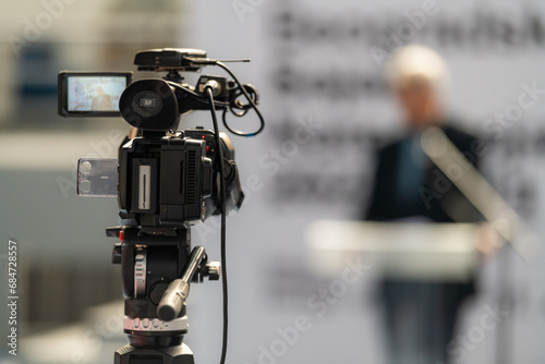 TV camera records a compelling male speaker on stage, delivering impactful insights on fair