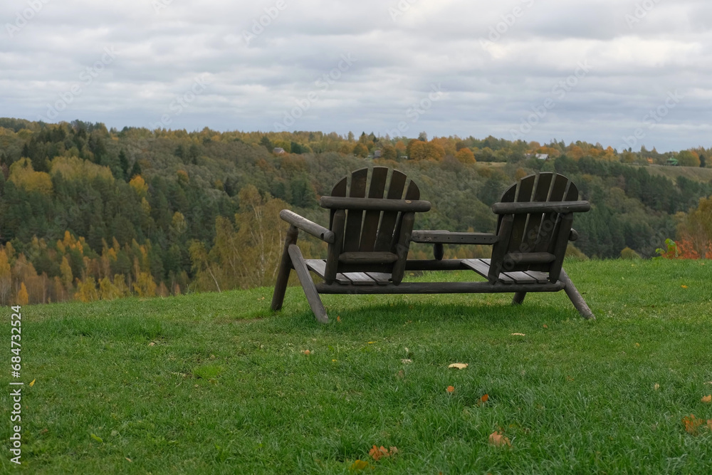Wooden chairs on cabin terrace with mountain view. Chilled Weekend Concept. Garden furniture. Beautiful landscaped backyard with great views. Hills landscape. Lounge armchairs outdoors. Wooden chairs on cabin terrace with mountain view. Chilled Weekend Concept. Garden furniture. Beautiful landscaped backyard with great views. Hills landscape. Lounge armchairs outdoors.