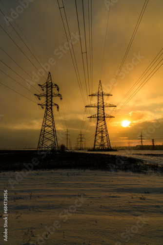 High voltage power line in a field at sunset on winter