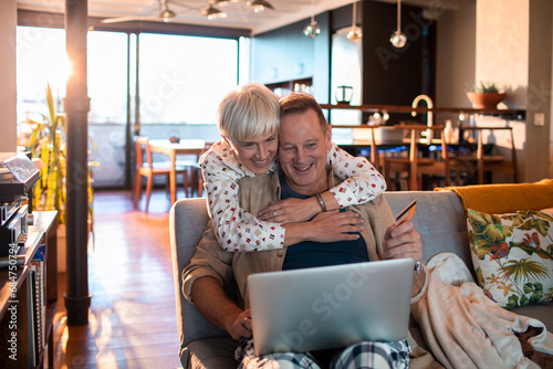 Happy mature couple online shopping from home photo