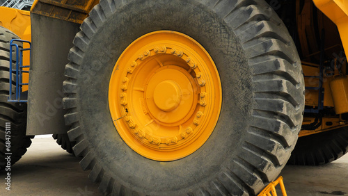 Close-up of a large car wheel. Tyres of a dump truck. A huge wheel on a yellow lorry. photo