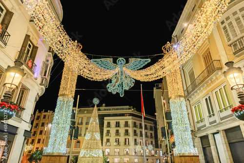 Angel of christmas lights decoration and Christmas tree on Marqués de Larios street with Plaza de la Constitución Constitution Square in Malaga, Andalusia, Spain