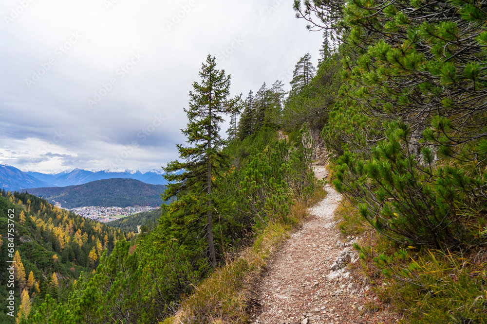 small path on top of a mountain with view towards alpine summits and cloudy sky	