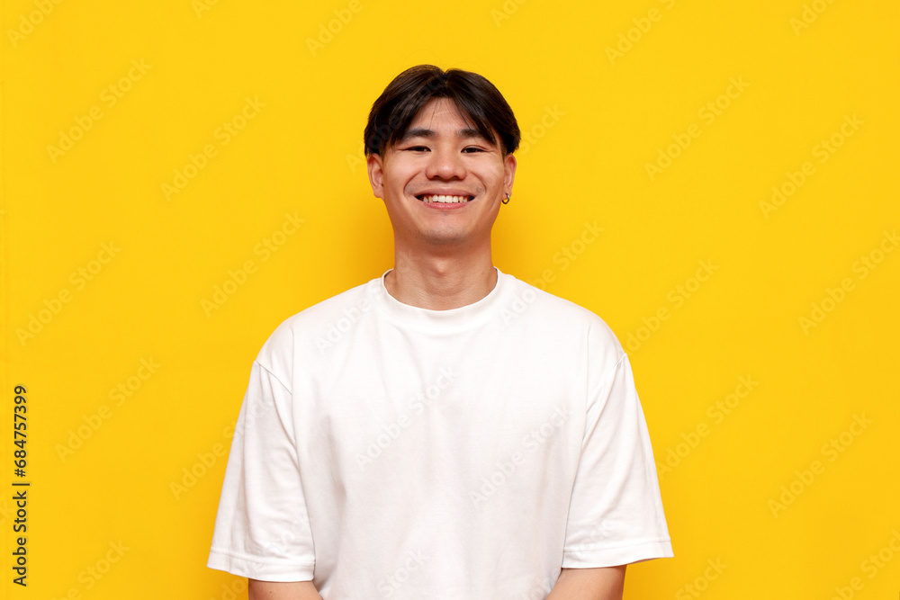 asian man in white t-shirt smiling on yellow isolated background