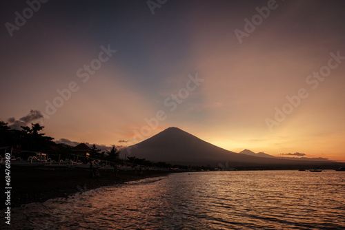 Sunset above Agung volcano from Amed with amazing sky. Black sand and traditional fishing boat.