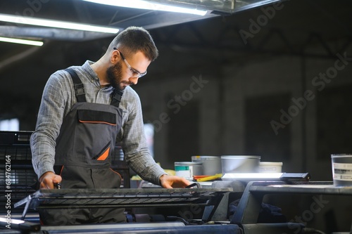 Man working in printing house with paper and paints