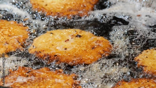 Traditional Polish potato pancakes food deep fried in oil, frying food slow motion bubbling oil crispy golden hash browns cooking on a pan, fat, oil, fatty foods concept, nobody, detail closeup shot