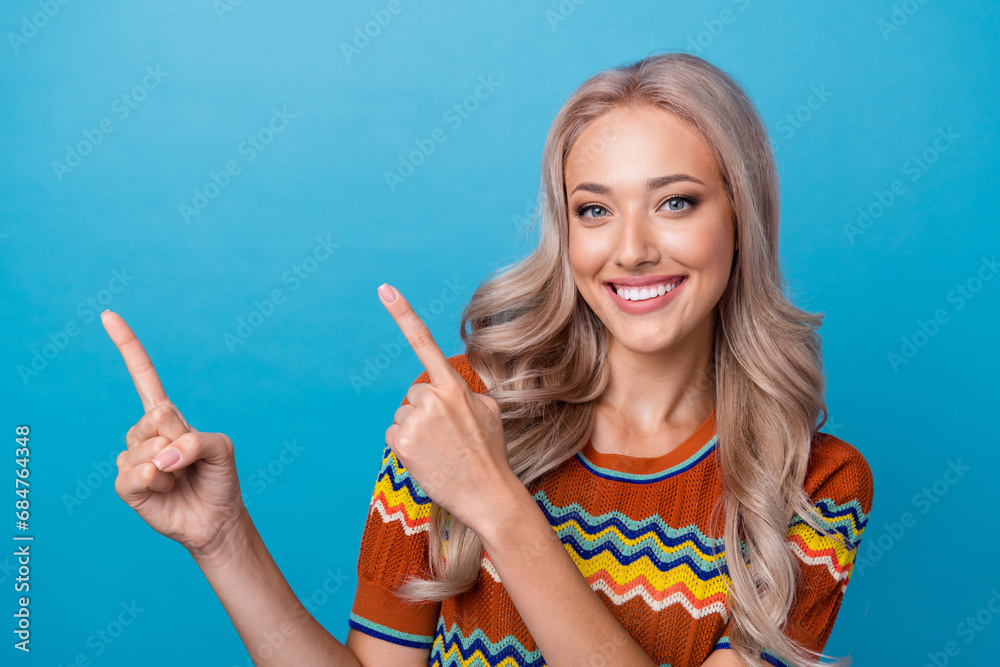Photo of adorable sweet girl dressed print shirt smiling pointing two fingers empty space isolated blue color background Photo of adorable sweet girl dressed print shirt smiling pointing two fingers empty space isolated blue color background
