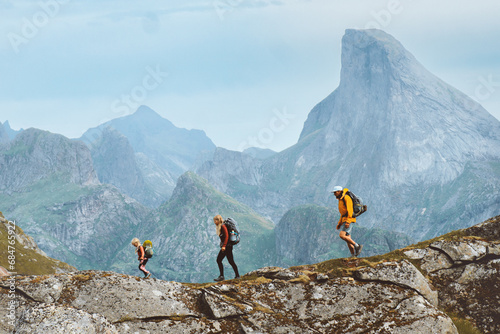 Family hiking together in Norway mountains, active vacations outdoor. Parents and child traveling healthy lifestyle adventure trip with mother, father and kid climbing in Lofoten islands