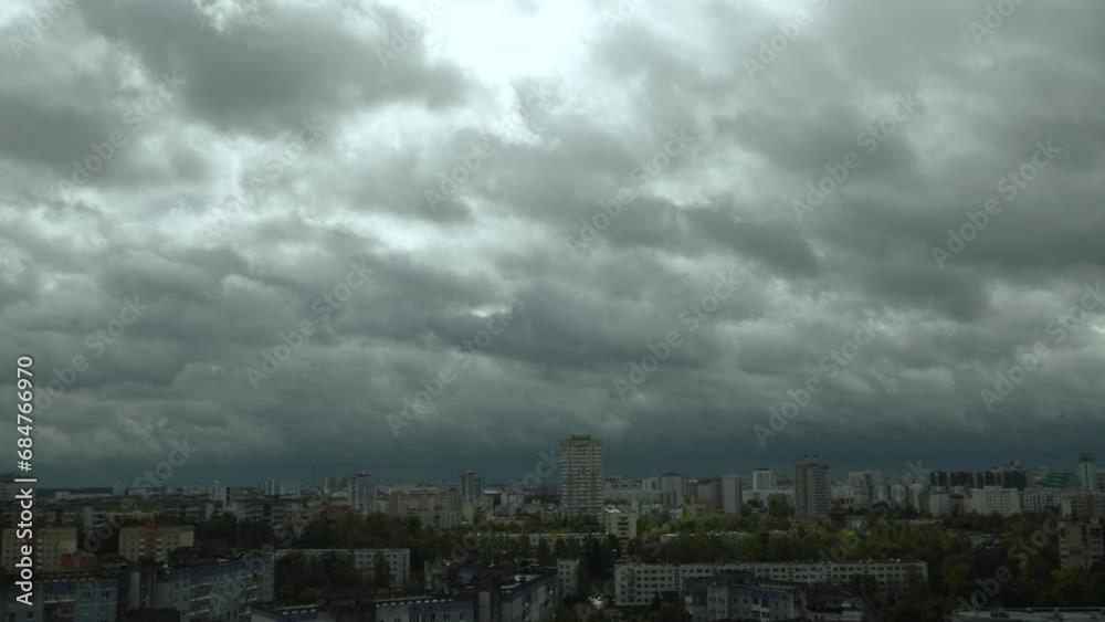 Zoom in timelapse view of roofs of big city with quickly moving grey gloomy clouds. Sun rays break through dense clouds in the sky. Cyclone with bad windy and uncomfortable weather. Zoom in timelapse view of roofs of big city with quickly moving grey gloomy clouds. Sun rays break through dense clouds in the sky. Cyclone with bad windy and uncomfortable weather.