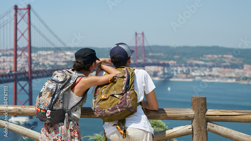 Tourists (young married couple) look at the suspension bridge over the Tagus River in Lisbon from the observation deck. photo