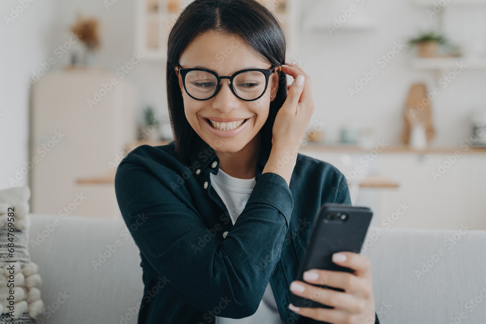 Joyful young woman enjoying a conversation on her smartphone at home Joyful young woman enjoying a conversation on her smartphone at home
