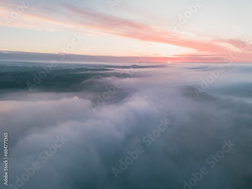 Aerial view of the floating clouds with the setting sun in the distance