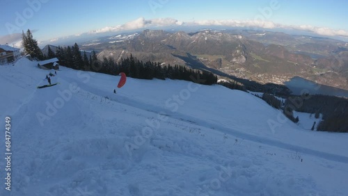 Paraglider starting from the top of Zwölferhorn in Sankt St. Gilgen, Austria. Amazing scene of extreme sports for winter activity at ski resort. photo