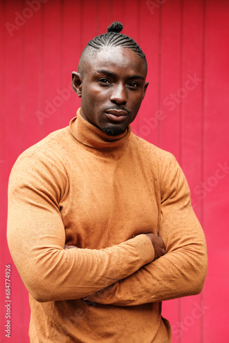 Handsome black male model posing in front of red wall.