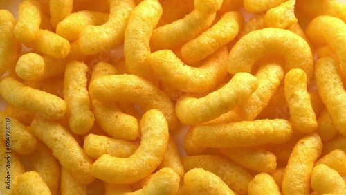 Cheesy corn chips rotates on plate top view. Crispy cheese snack. Crispy fluffy corn sticks for breakfast