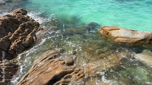 Sea waves with clear water crushing over the rocks during beautiful sunny day. 