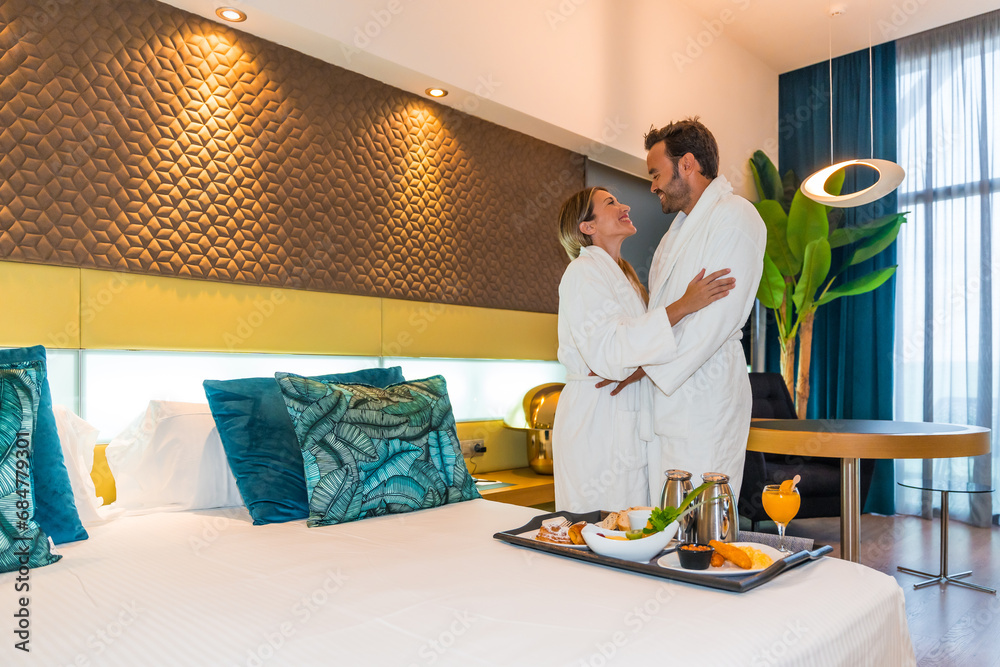 Couple on a luxury hotel room with breakfast on bed