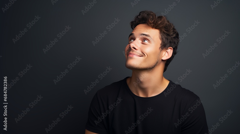 A young and attractive man is thinking deeply and imagining things, while looking up at an empty space A young and attractive man is thinking deeply and imagining things, while looking up at an empty space