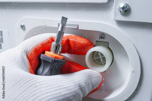 Service engineer checking the water filter of the washing machine inlet valve. Cleaning the water hose mesh filter.