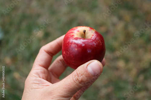 Young woman is holding red apple close
