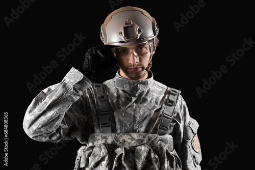 Young male soldier in helmet on black background