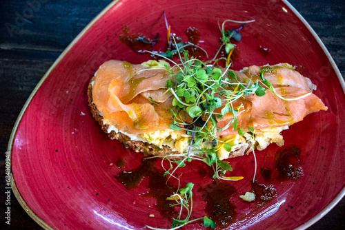 a bird's eye view of a slice of toast topped with scrambled eggs and smoked salmon close up.