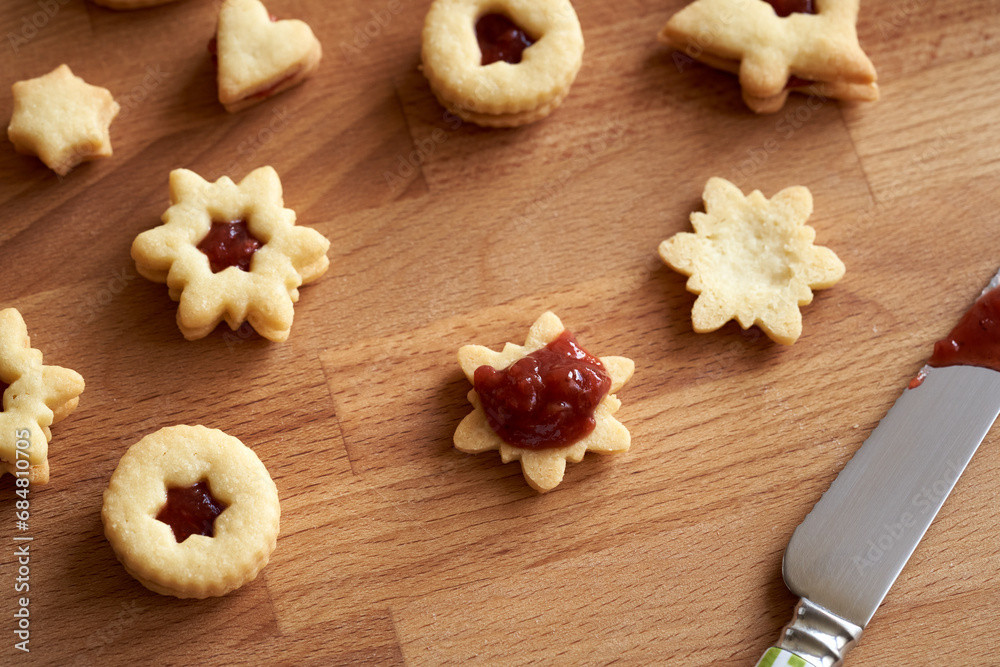 Filling homemade Linzer Christmas cookies with strawberry marmalade, top view Filling homemade Linzer Christmas cookies with strawberry marmalade, top view