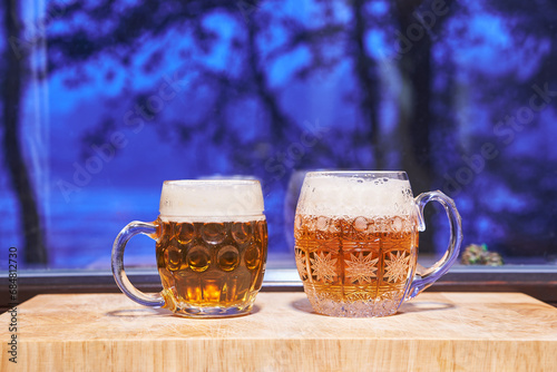 Two pints of lager beer pilsner type form Czech Republic in the traditional czech style mugs in front of window during the cold winter evening. Special kind of beer is traditional drink for Christmas.