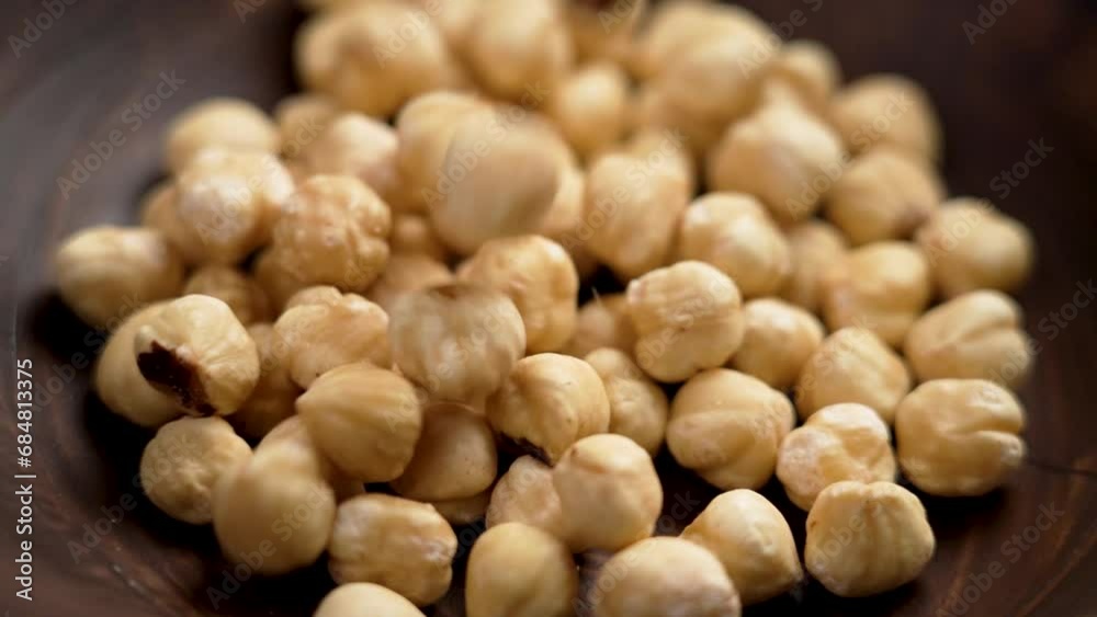 Roasted peeled hazelnut kernels falling into a wooden bowl. Shelled filbert. Rotation. Slow motion Roasted peeled hazelnut kernels falling into a wooden bowl. Shelled filbert. Rotation. Slow motion