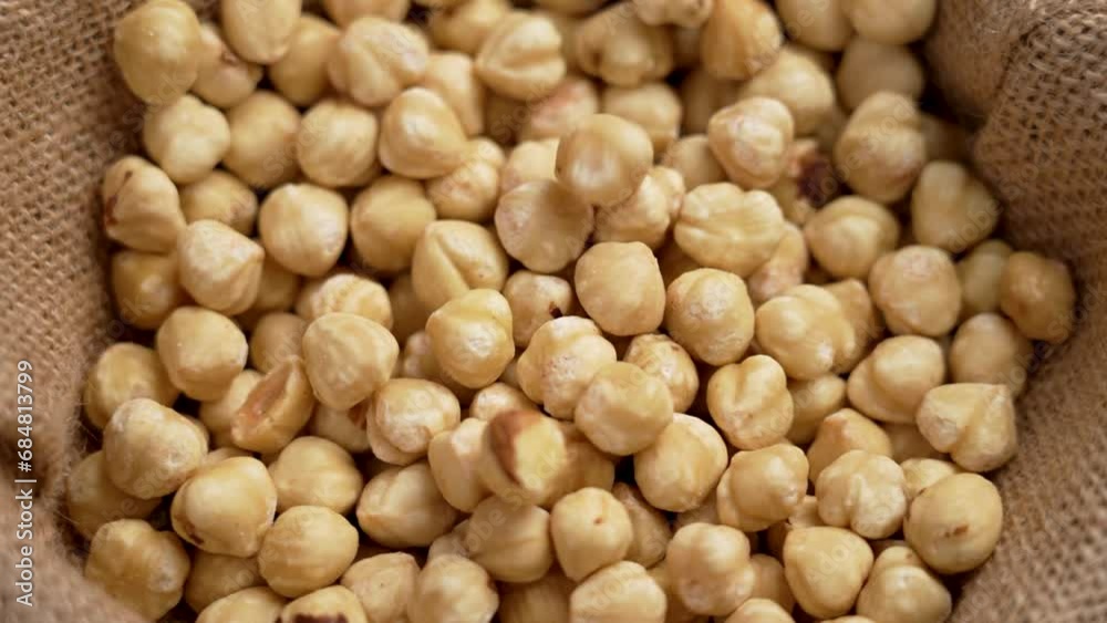 Peeled hazelnut kernels. Shelled filbert nuts falling in slow motion close up on a burlap cloth Peeled hazelnut kernels. Shelled filbert nuts falling in slow motion close up on a burlap cloth