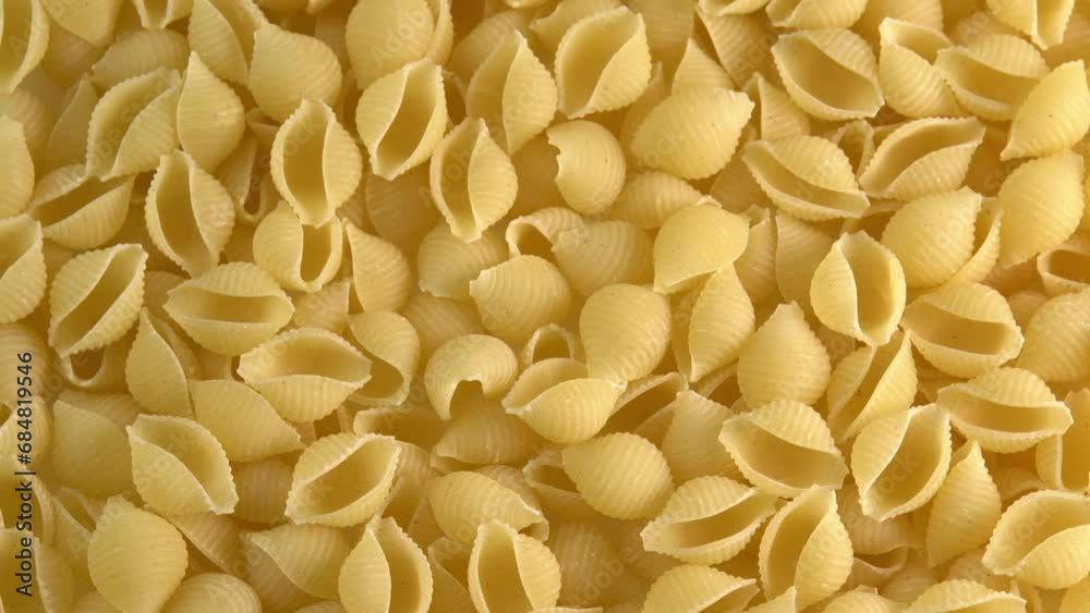 Italian pasta conchiglie rigate shell shaped rotating background closeup top view side light. Durum wheat flour macaroni conchigliette Italian pasta conchiglie rigate shell shaped rotating background closeup top view side light. Durum wheat flour macaroni conchigliette