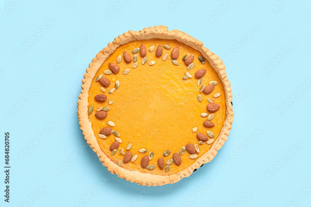 Delicious pumpkin tart with almond and seeds on blue background Delicious pumpkin tart with almond and seeds on blue background