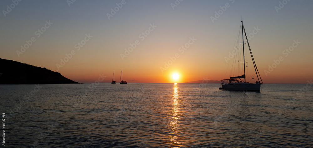 Peaceful sunset over the sea with silhouette of sailboat