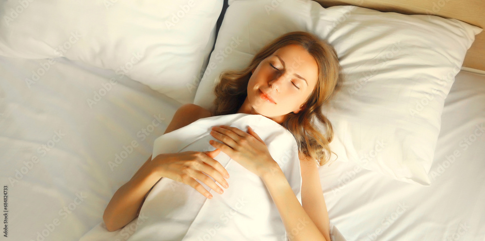 Young woman sleeping lying in bed on white soft comfortable pillow in room at home Young woman sleeping lying in bed on white soft comfortable pillow in room at home