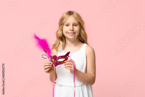 Funny little girl with carnival mask on pink background photo