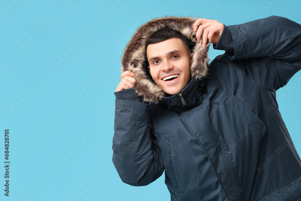 Young man in stylish puffer jacket on blue background Young man in stylish puffer jacket on blue background