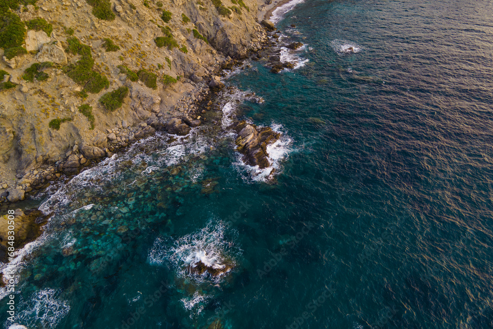 Sea waves crashing of majestic rocks reef and cliffs, aerial view. Drone shot of powerful sea water on coastline