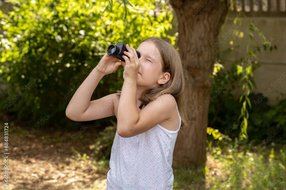 Young school age child, girl looking up into the sky through a magnifying monocular watching birds, searching seeking looking for something in the sky. Opportunities and possibilities abstract concept Young school age child, girl looking up into the sky through a magnifying monocular watching birds, searching seeking looking for something in the sky. Opportunities and possibilities abstract concept