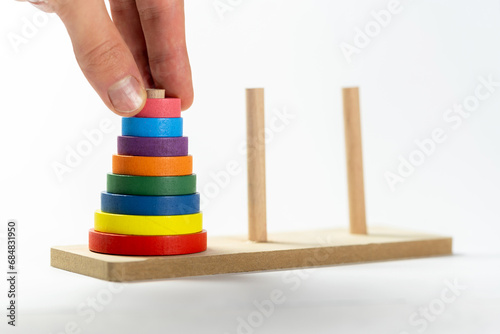 Man solving a tower of Hanoi moving elements with his hand, puzzle recursive algorithm computer science problems abstract, object closeup, toy. Algorithmic problem solving, IT job interview questions