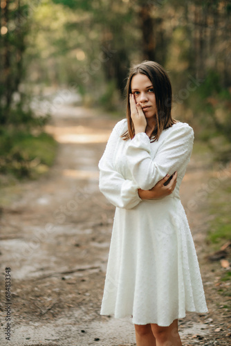 a young girl in a white dress in a green pine tree the forest