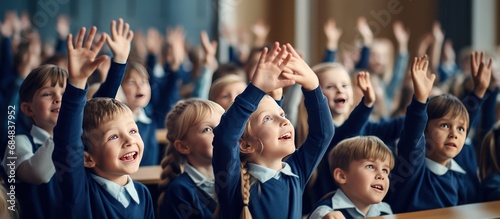 Group happy of student or children wearing blue uniforms raising hands in classroom © artpray