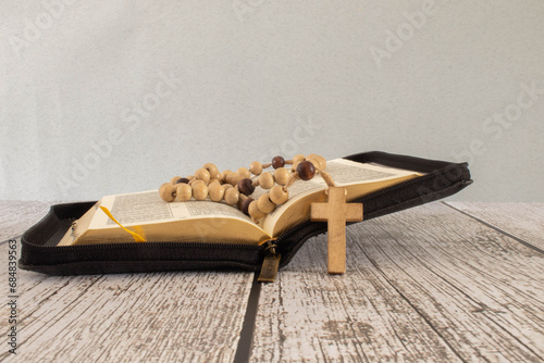 Open bible with rosary beads on wooden table photo