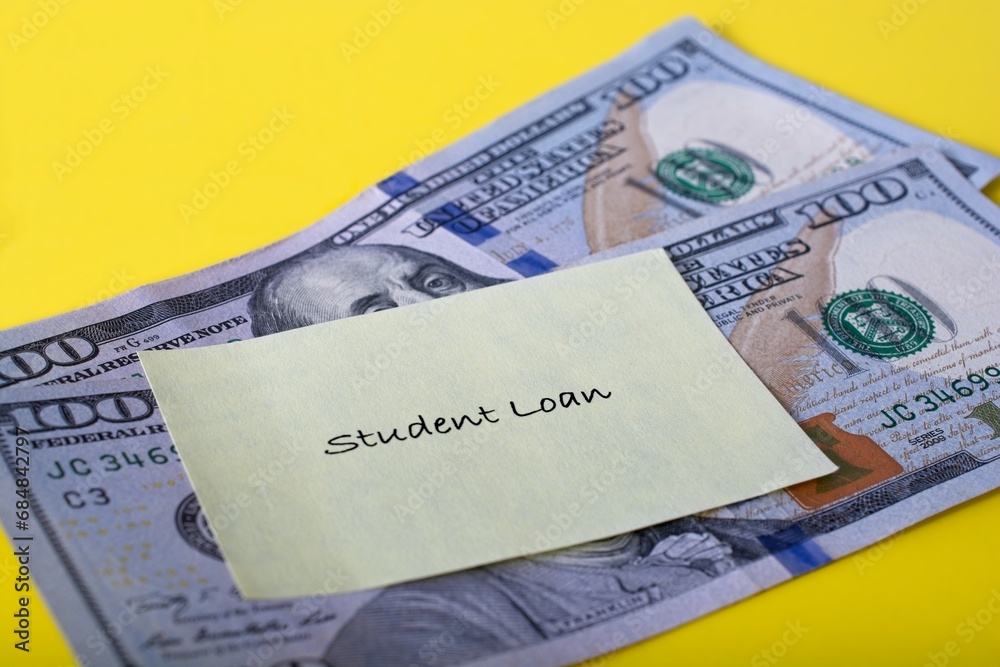 Close up debt reminder slip labeled ‘Student Loan’ posted to two one hundred dollar bills Close up debt reminder slip labeled ‘Student Loan’ posted to two one hundred dollar bills