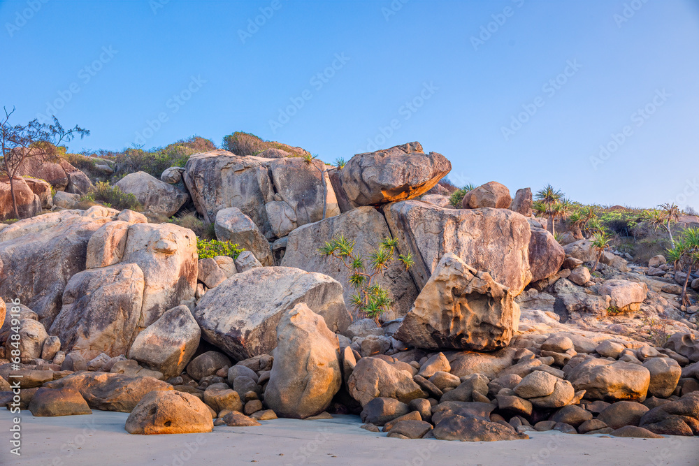A jumble of granite boulders on the edge of the tropical beach at Rose Bay in Bowen in the Whitsundays region of tropical Queensland, Australia. A jumble of granite boulders on the edge of the tropical beach at Rose Bay in Bowen in the Whitsundays region of tropical Queensland, Australia.