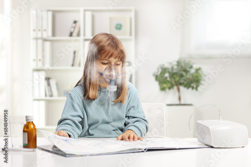 Little girl reading a book and using a nebulizer photo