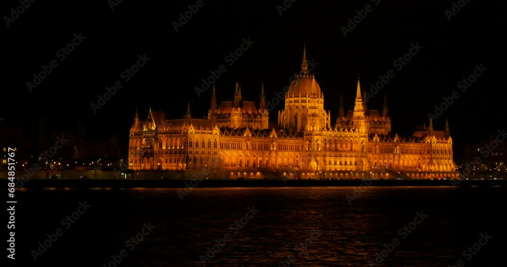 Hungary parliament building against river. A view of Hungary parliament building in illumination by the Danube river during night time. Hungary parliament building against river. A view of Hungary parliament building in illumination by the Danube river during night time.