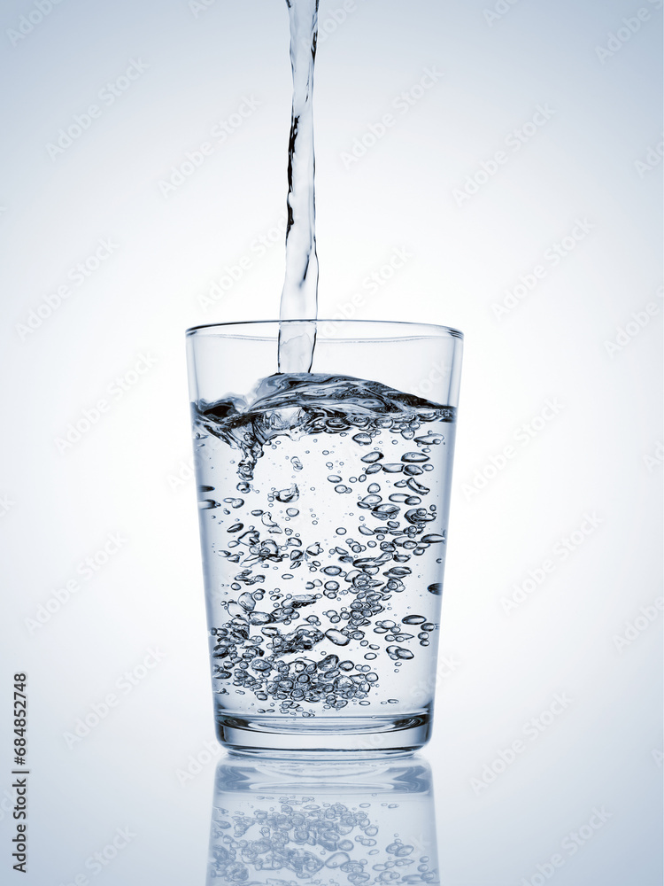 Water pouring in a glass with bubbles on blue background Water pouring in a glass with bubbles on blue background