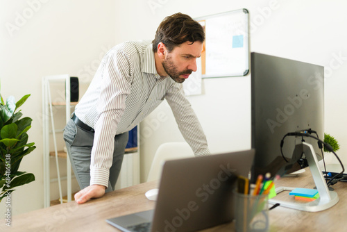 Attractive broker looking at the computer while buying stocks